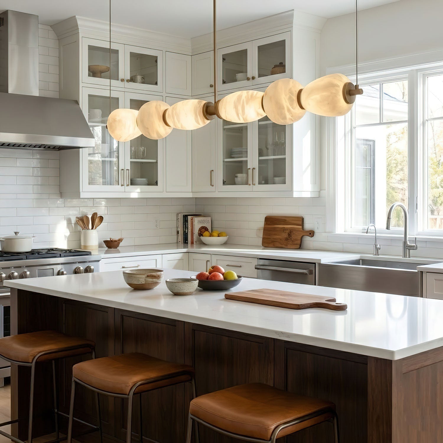 Clérachic Pebble chandelier lighting a white kitchen island with tan leather counter stools.