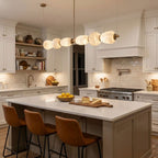 Clérachic Pebble chandelier above a marble-topped island in a cream shaker kitchen.