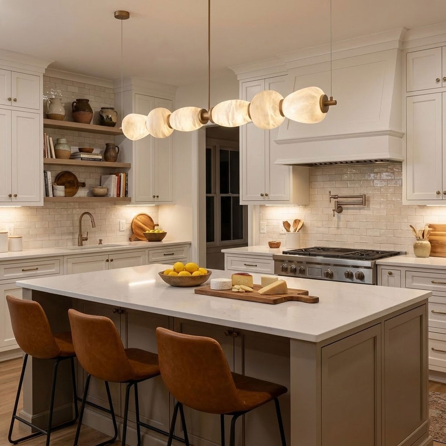 Clérachic Pebble chandelier above a marble-topped island in a cream shaker kitchen.