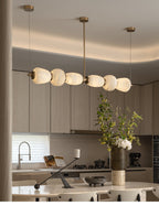 Clérachic Pebble chandelier in a pale oak kitchen, hanging above the island and cut branches.