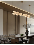 Clérachic Pebble chandelier above a dark dining table in a room lined with tall panelled doors.