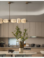 The Clérachic Pebble chandelier lit over a rounded island in a soft-toned modern kitchen.