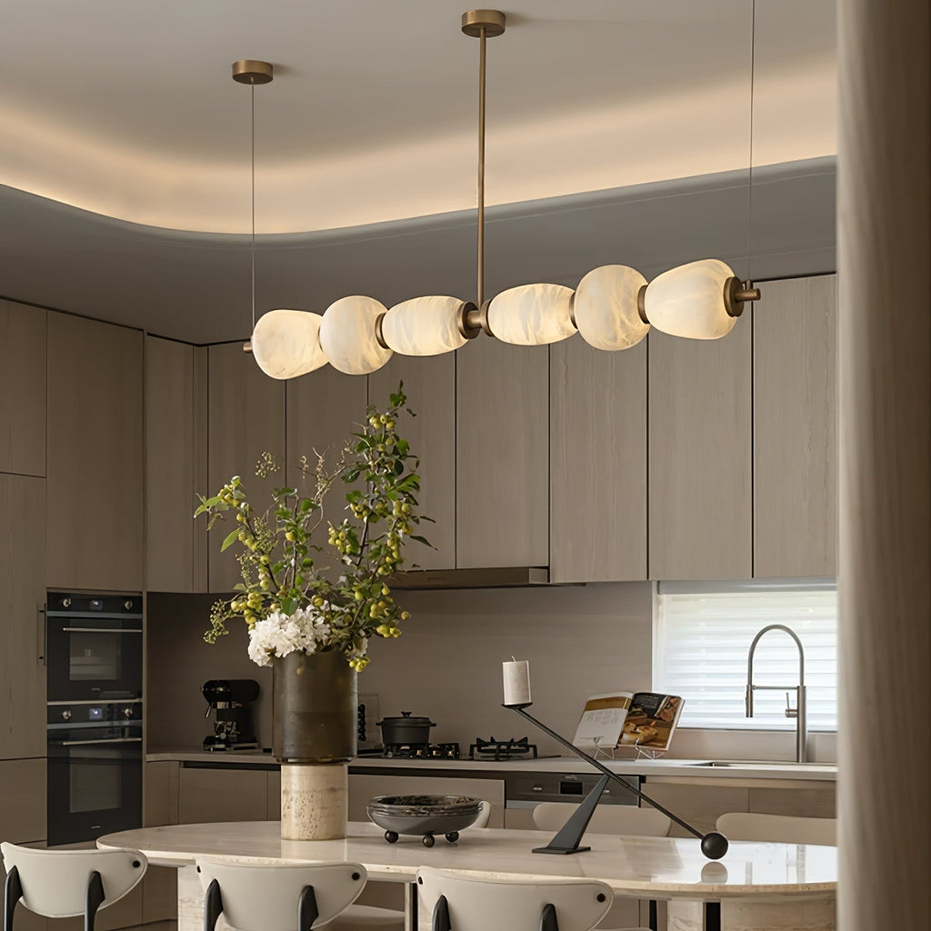 Clérachic Pebble chandelier seen close in an oak kitchen, alabaster forms glowing warm.