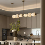 Clérachic Pebble chandelier seen close in an oak kitchen, alabaster forms glowing warm.