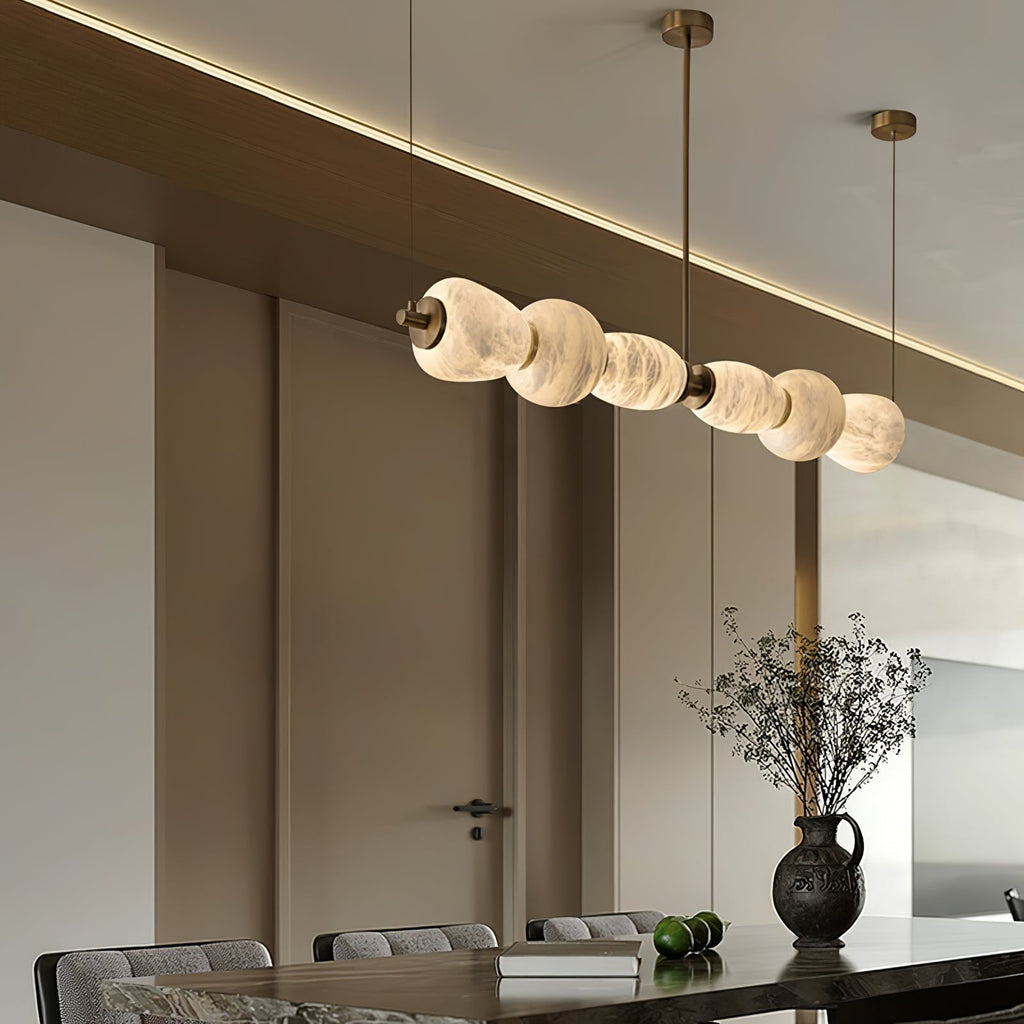 Clérachic Pebble chandelier reflected in a mirrored wall above a dark stone dining table.