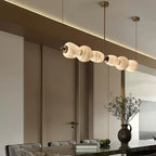 The Clérachic Pebble chandelier over a dining table, brass stems dropping from the ceiling.