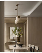 Clérachic Pebble chandelier viewed end-on in a pale oak room, stones lining up along the rod.
