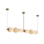 Clérachic Pebble chandelier on white, three brass drops holding the alabaster bar level.