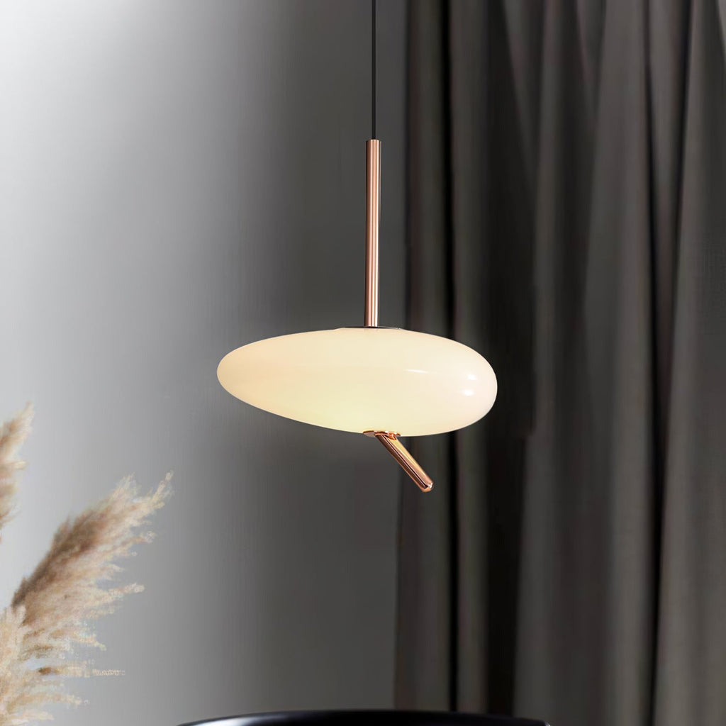 The Clérachic pendant casts a warm glow beside a dark curtain, with dried pampas grass framing the foreground.