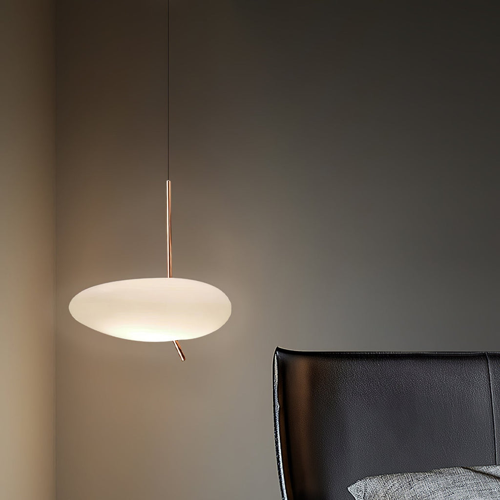 Clérachic pebble pendant lit beside a black leather chair and a gray textured cushion in a dim charcoal room.