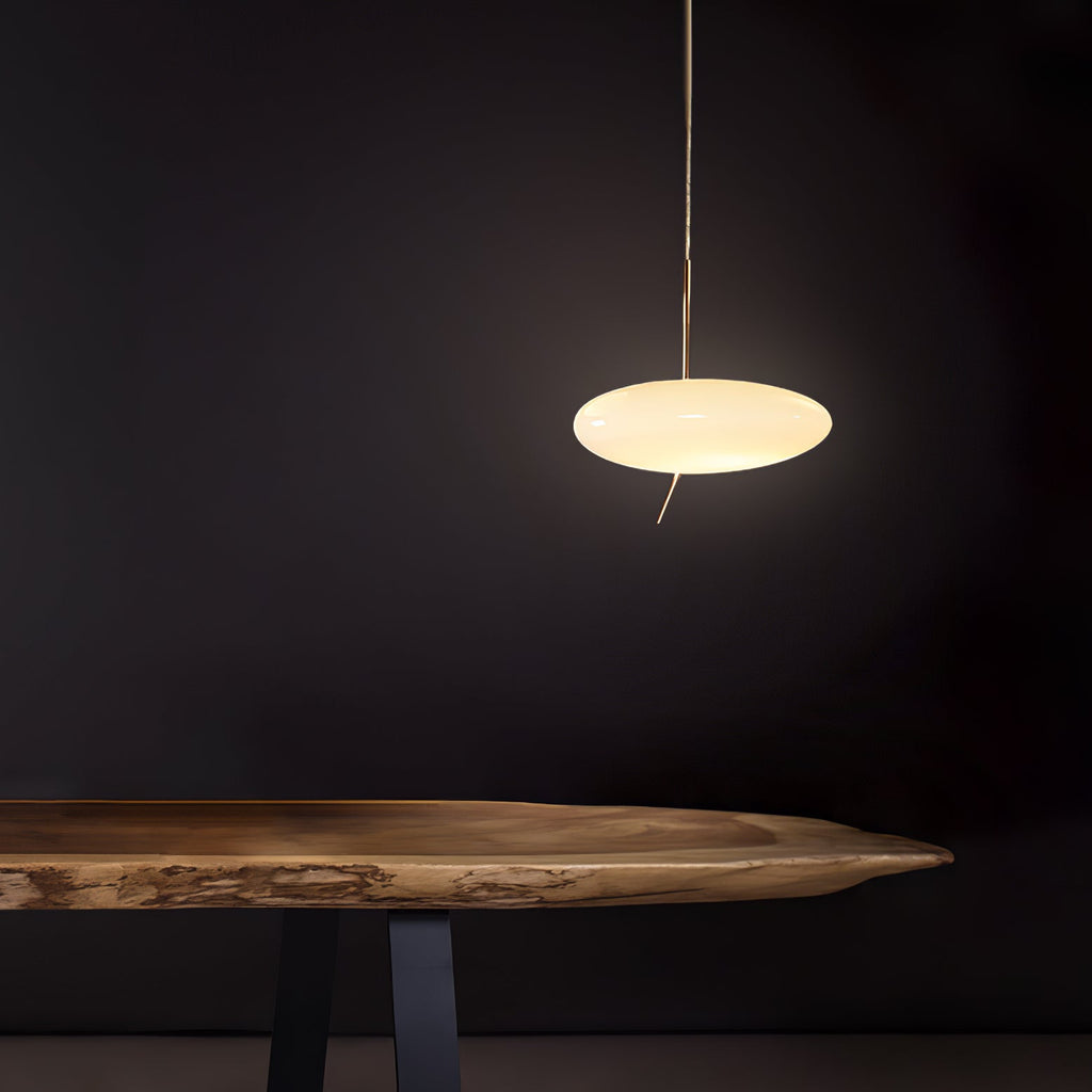 A hand reaches toward the glowing Clérachic pendant, set against a cream wall with classic crown molding.
