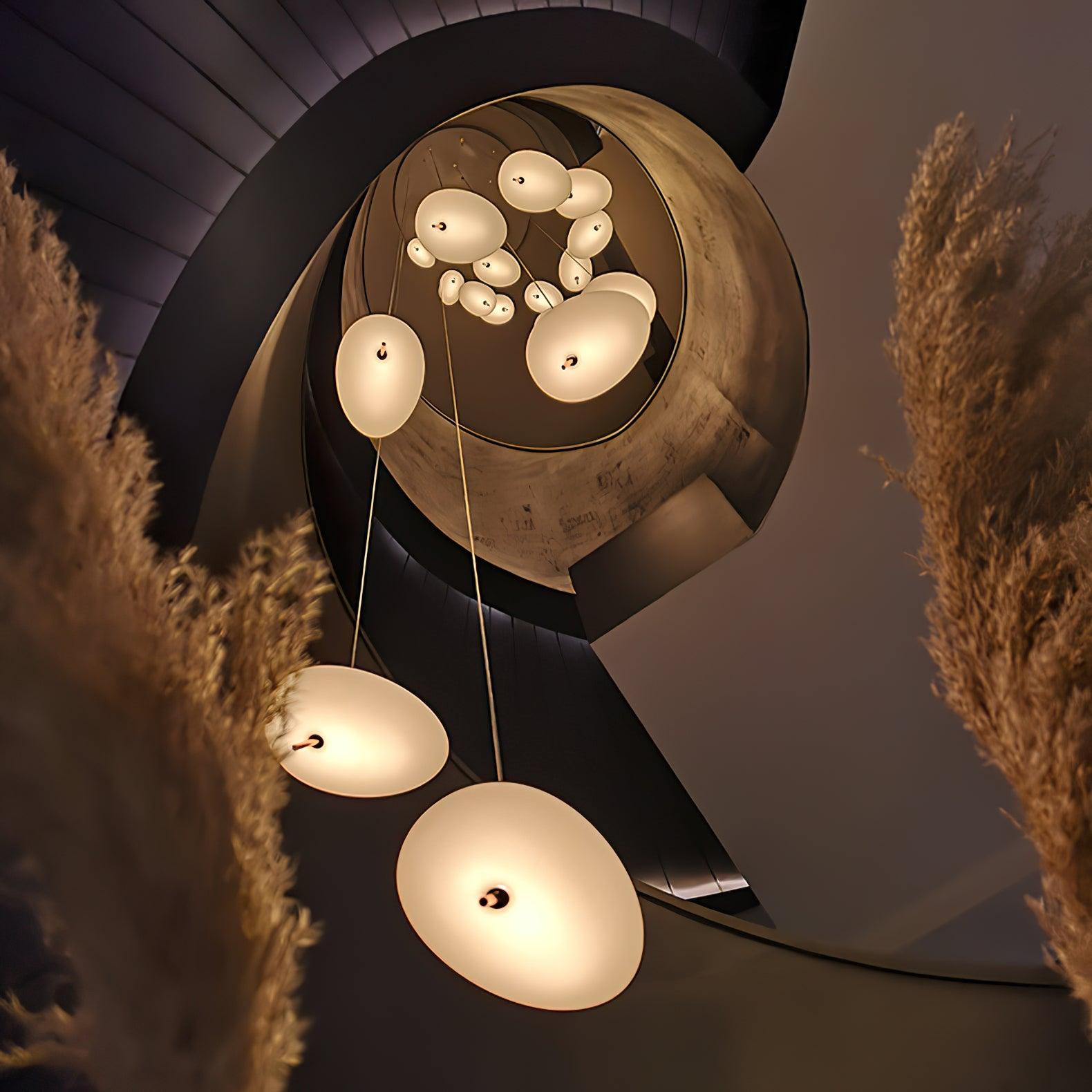 The Clérachic pendant's mounting hardware shown up close, framed by stacked books and a vase of pink roses.