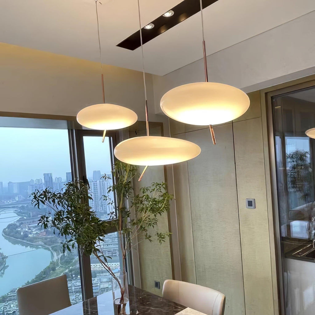 Three Clérachic pebble pendants light a dining table with a river and city skyline visible through the window.