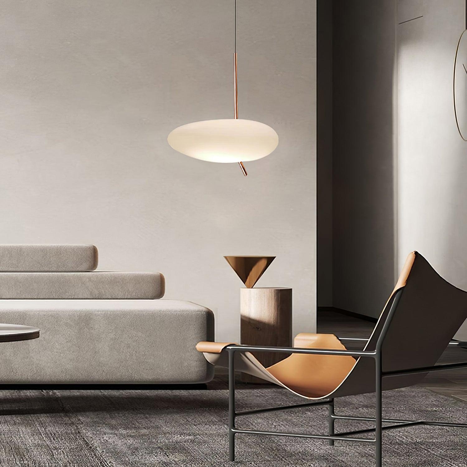 Clérachic pendant lighting a modern gray living room beside a leather sling chair and a cone-shaped side table.