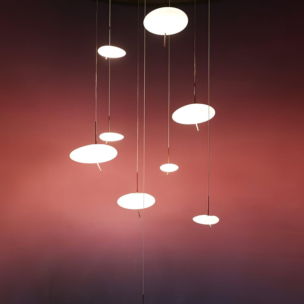 Seven Clérachic pebble pendants cluster at varying heights against a dusty rose gradient wall.
