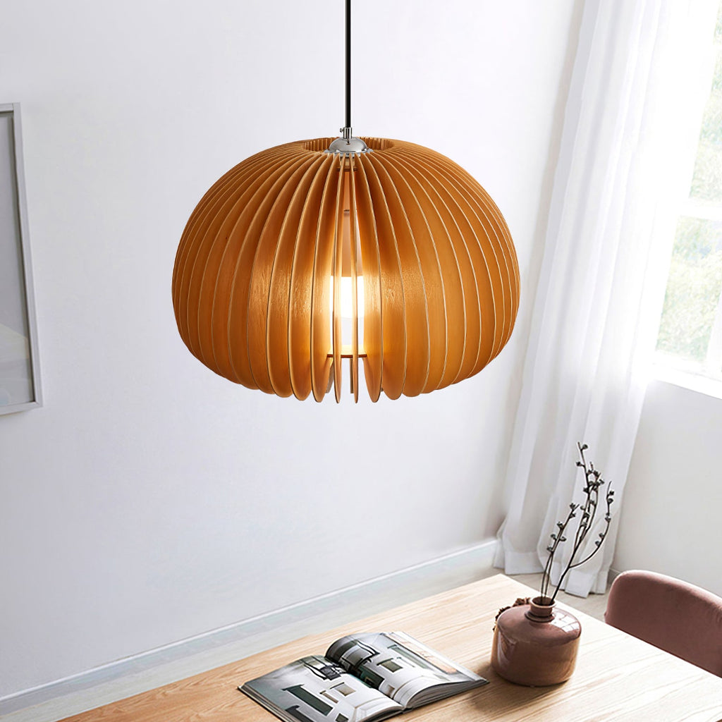 A Clérachic natural wood pendant hung in a corner by a window with a sheer curtain, above a wooden table with a magazine and a vase.