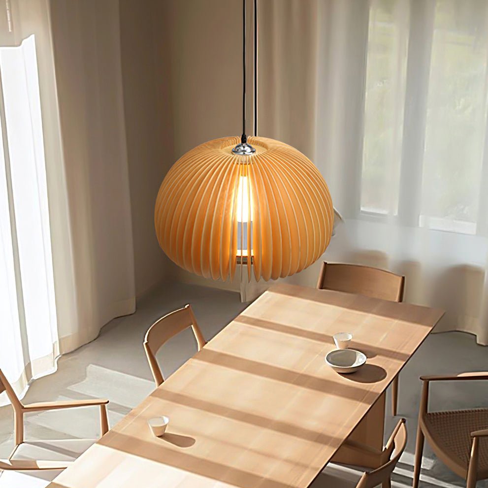Clérachic slatted pendant lit over a long light wood table with simple chairs, in a bright room with sheer curtains at the window.