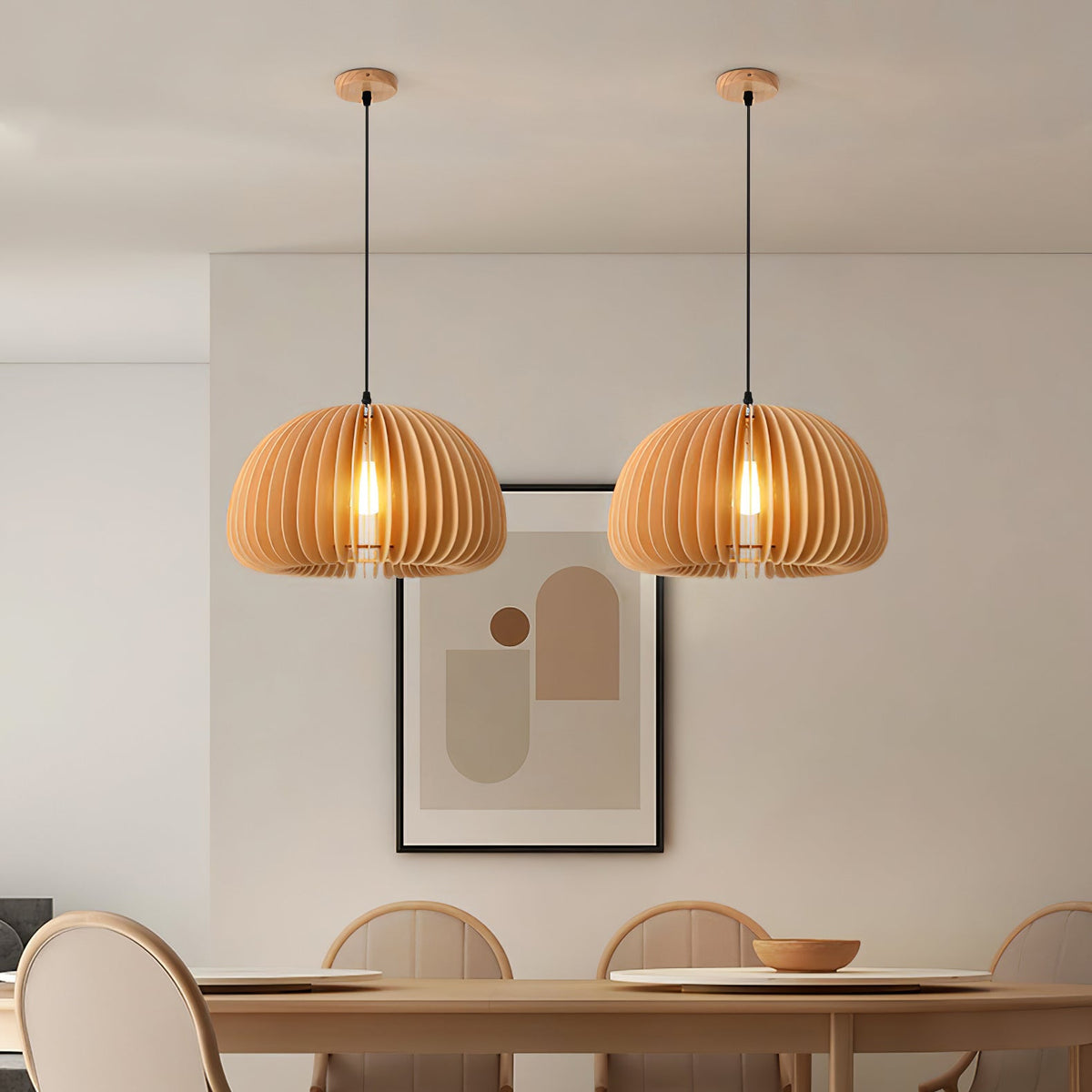 Two Clérachic wood slat pendants over a dining table with round-backed chairs, in front of a framed abstract print on a pale wall.