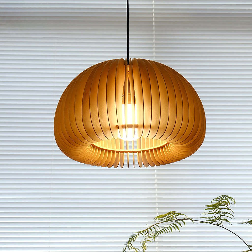 Looking up into this Clérachic slatted pendant, the bulb glowing at the centre of the open base, with a blind and ferns behind.
