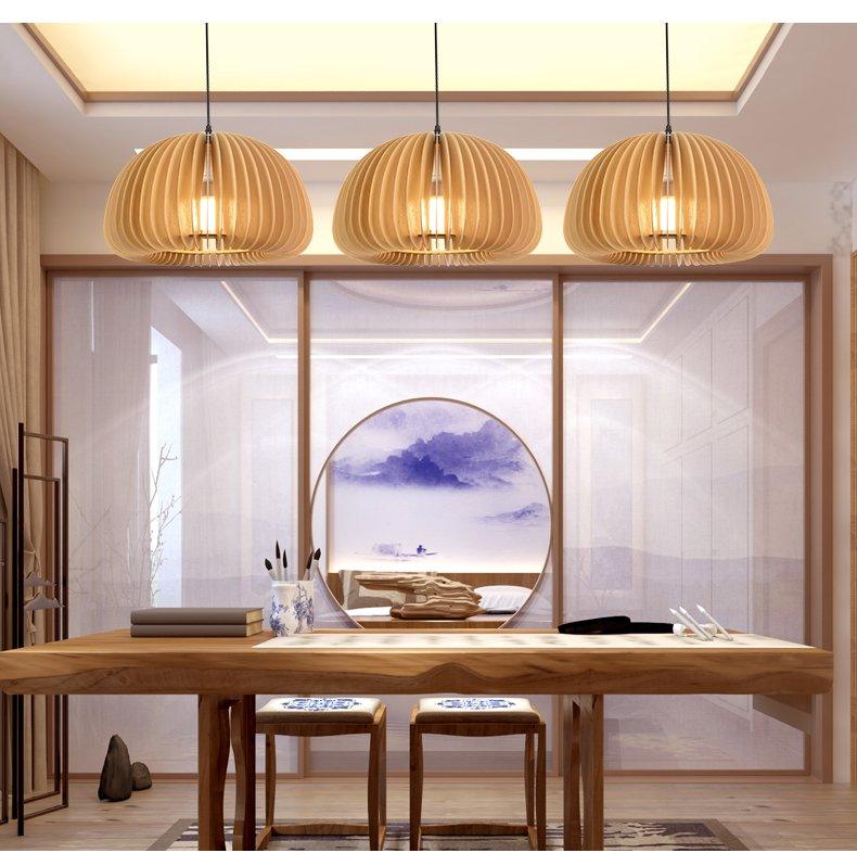 Three Clérachic slatted pendants in a row above a long wooden desk, in a calm study with a round window and a mountain painting.
