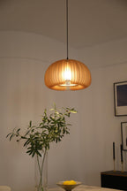 Clérachic slat pendant above a dining corner with a vase of olive branches, a dish of lemons and framed prints on the wall.