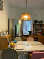 A Clérachic wooden pendant in a home kitchen with a steel fridge, a window and a table laid with fruit and a placemat.