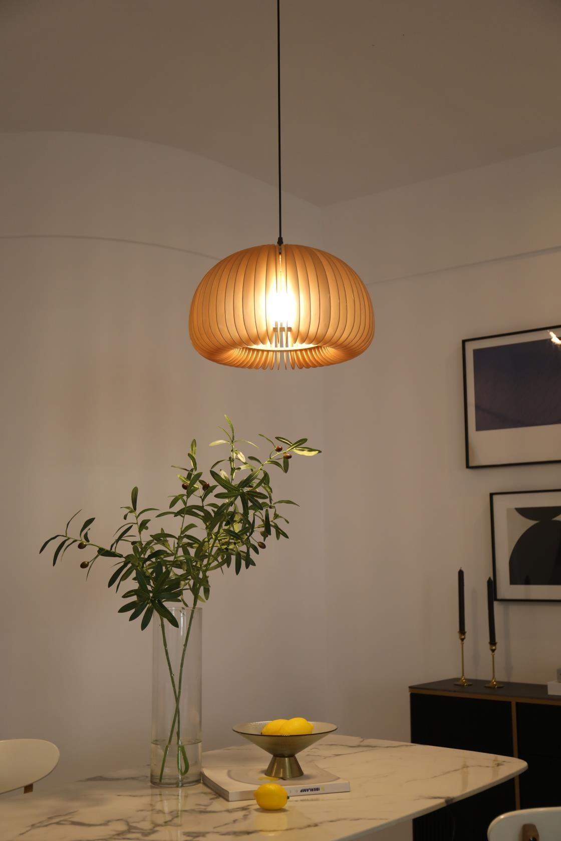 Lit Clérachic slatted pendant above a marble-topped table with a green stem in a glass vase and a dish of lemons.
