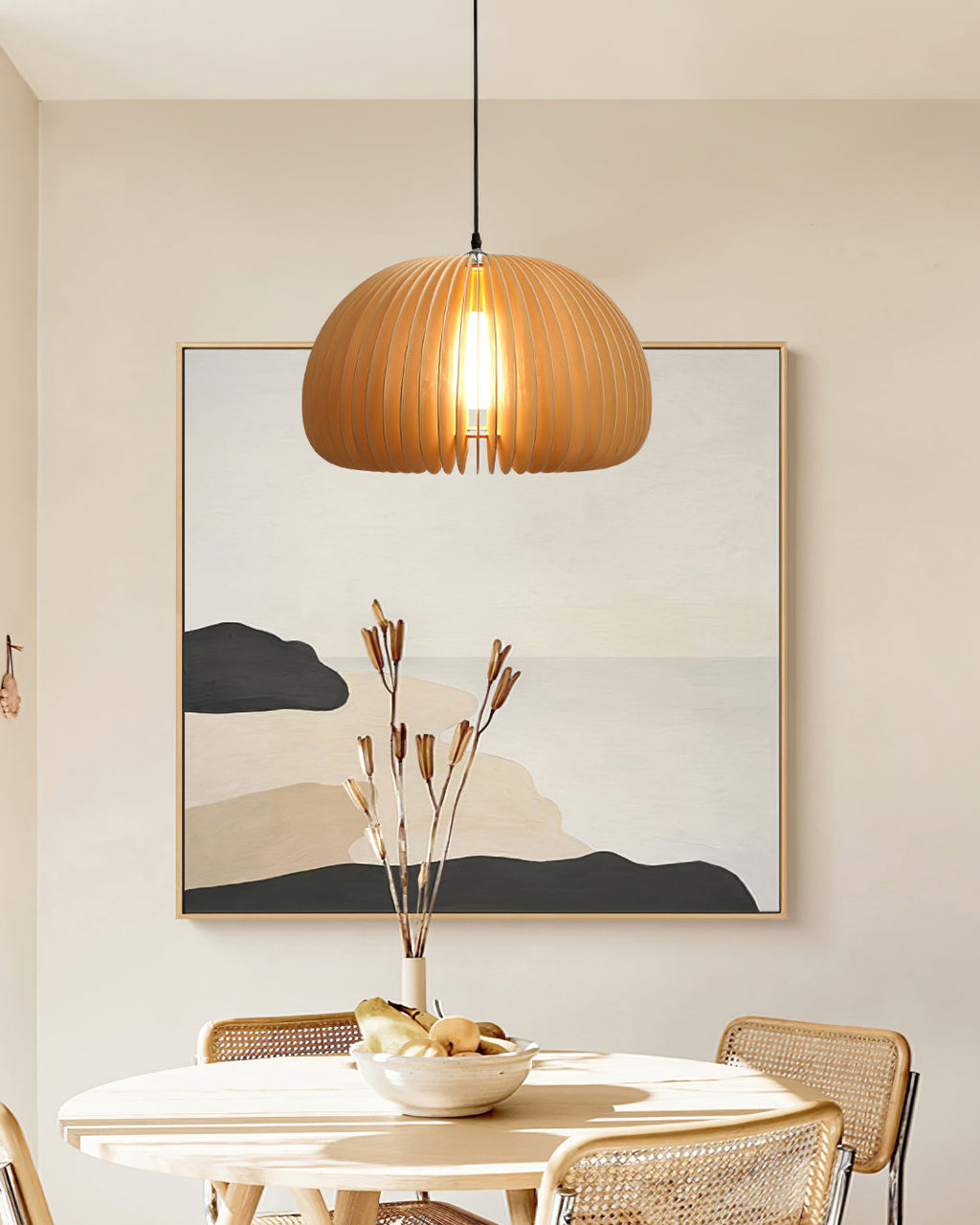 Clérachic slatted pendant in front of a framed abstract print above a round table with a bowl of fruit and rattan chairs.
