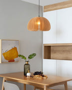 Clérachic slatted pendant in a bright dining corner, with a framed abstract picture, a green vase and a wooden shelf behind.
