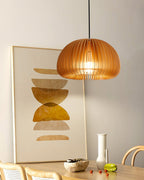 Clérachic wooden pendant lit beside a large abstract print in ochre, above a table with a vase and a pale bowl of food.