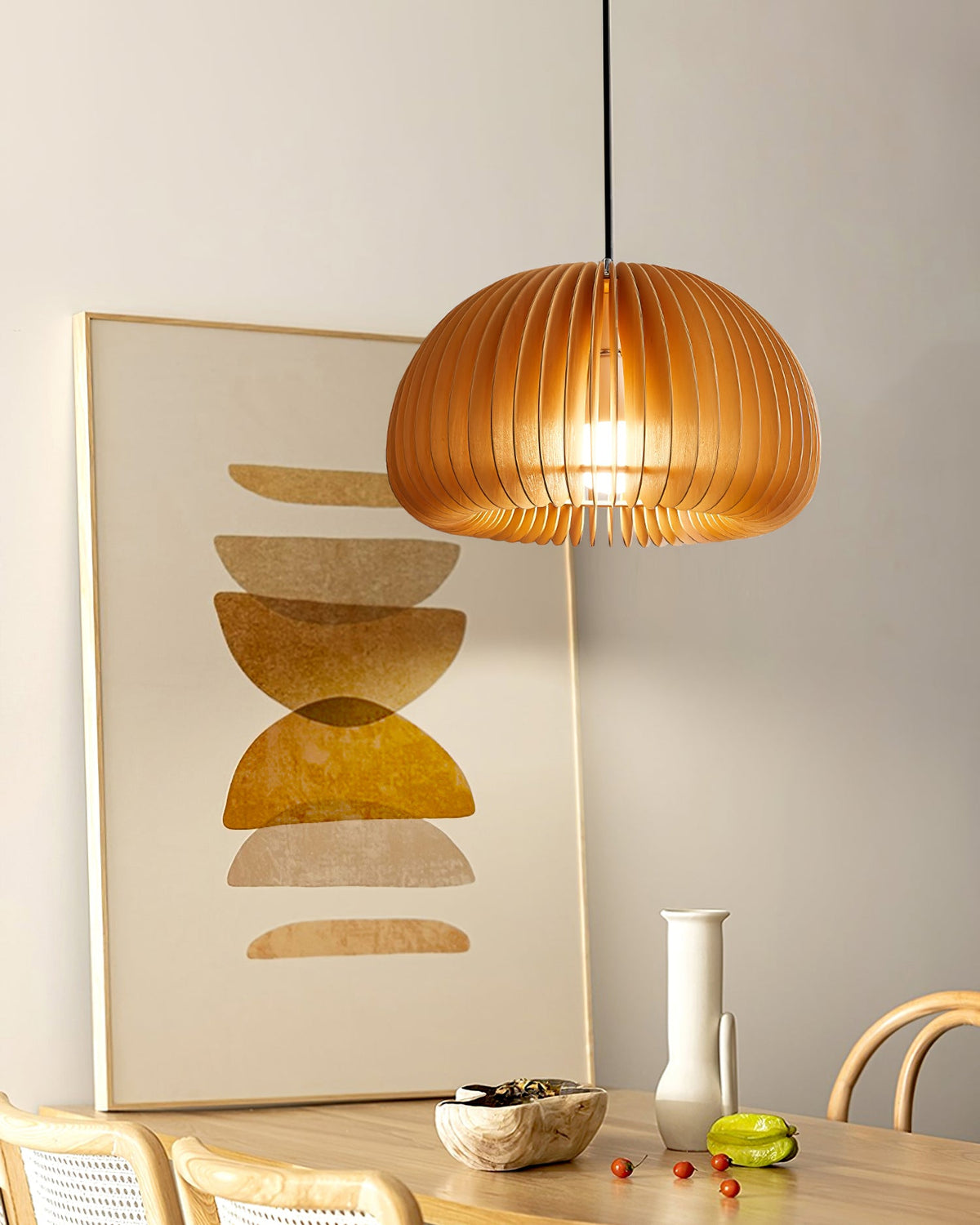 Clérachic wooden pendant lit beside a large abstract print in ochre, above a table with a vase and a pale bowl of food.