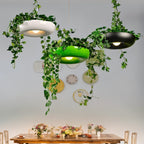 Clérachic planter-style pendants in white, green and black hanging side by side with trailing ivy over a flower-laden dining table.