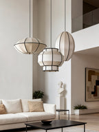 Three ribbed fabric pendants from this Clérachic fixture hang in varied shapes in an open living space near a stone bust.