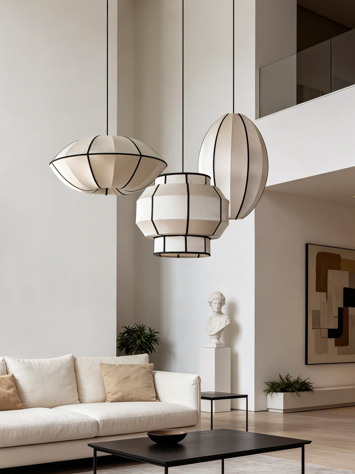 Three ribbed fabric pendants from this Clérachic fixture hang in varied shapes in an open living space near a stone bust.