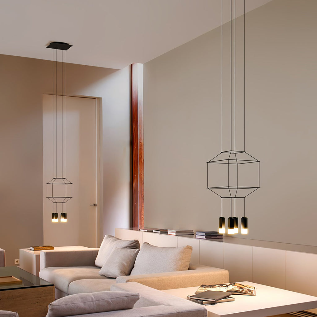 Two wireframe pendants of different sizes hang in a living room beside a pale sofa, a Clérachic pair with small black lights.