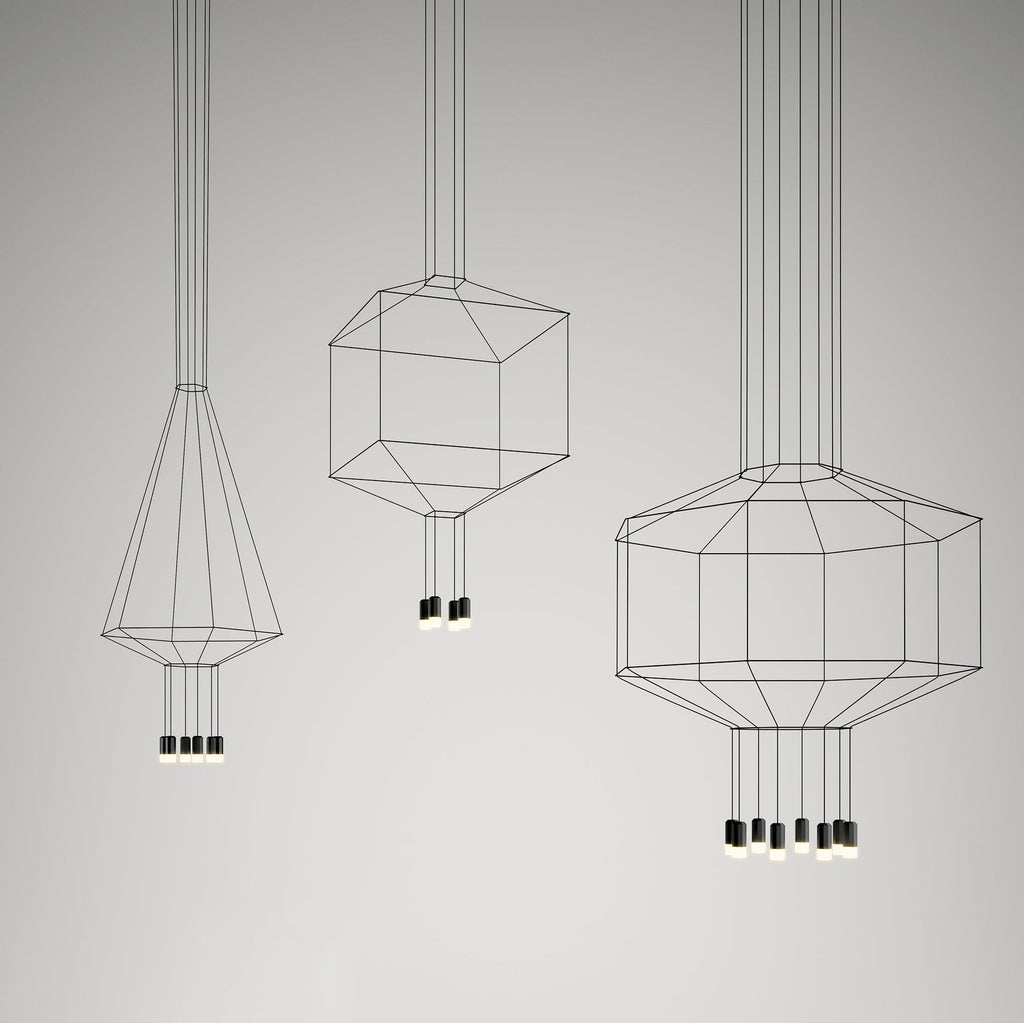 Three Clérachic wireframe pendants in a cone, cube and octagon shape, each with small black lights, on a grey studio backdrop.