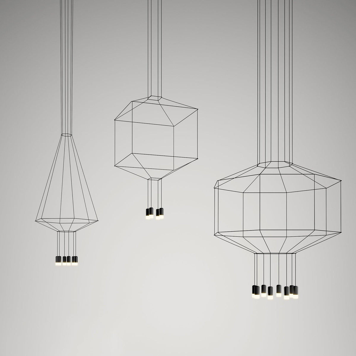 Three Clérachic wireframe pendants in a cone, cube and octagon shape, each with small black lights, on a grey studio backdrop.