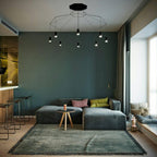 Wide black wireframe pendant with a canopy and small lights spreading across a teal living room, from Clérachic.