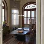 Clérachic wireframe pendant over a dark oval table in a room with tall arched windows and wood floors.