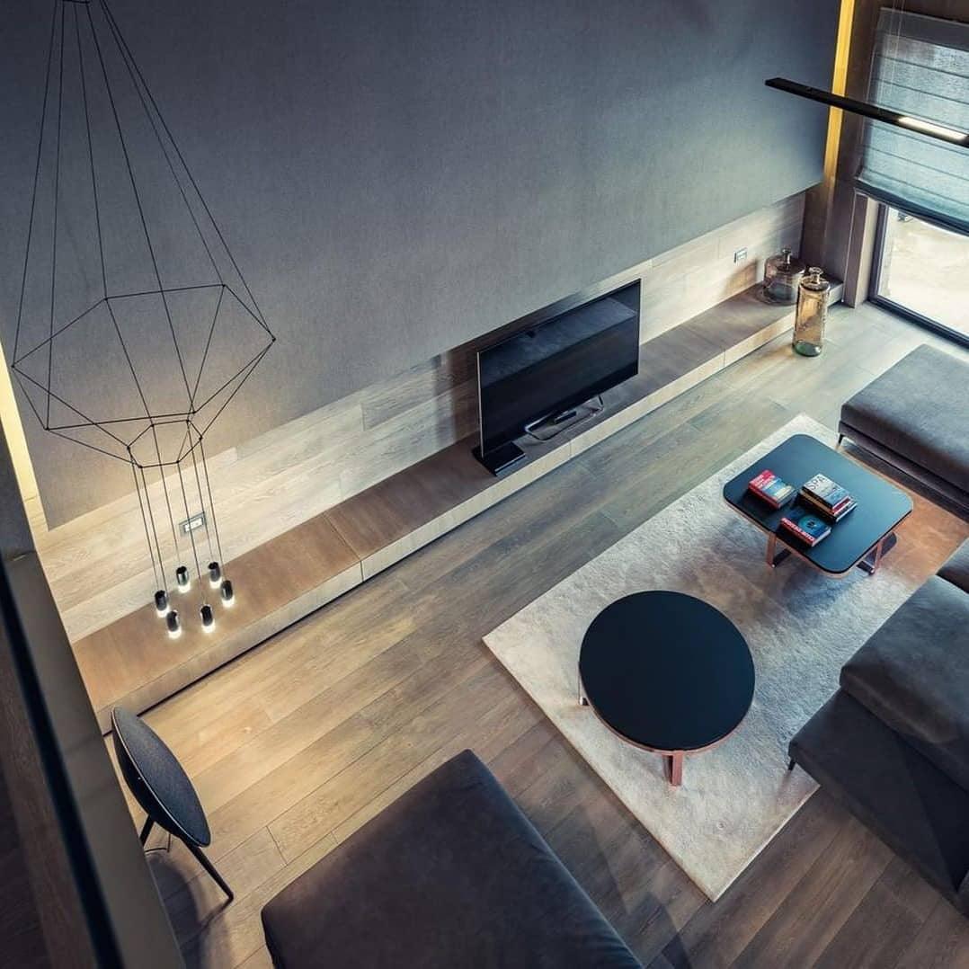 Wireframe pendant seen from above in a living room with a dark wall, a wood floor and a round black coffee table, from Clérachic.