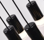 Close view of black cylindrical light heads with perforated caps and frosted diffusers, on this Clérachic pendant.