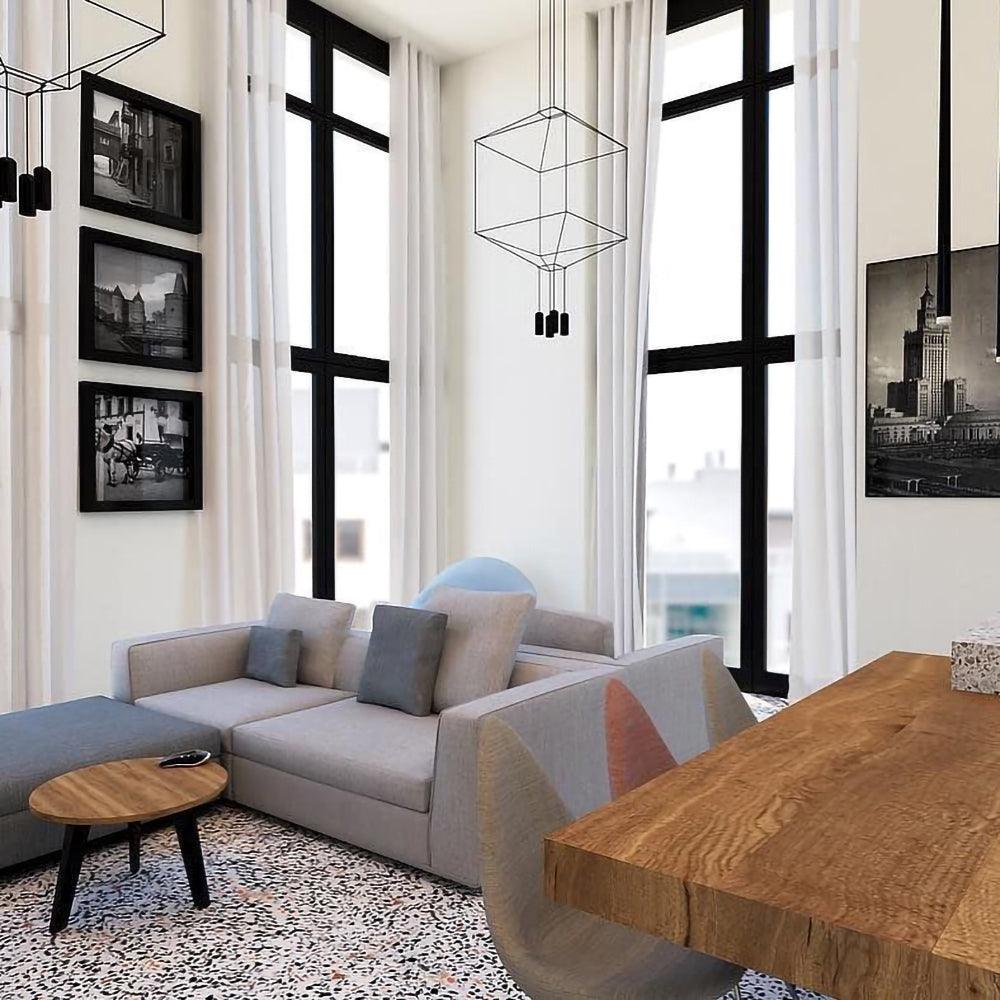 Cube wireframe pendant in a tall living room with a grey sofa, black-framed windows and framed prints, from Clérachic.