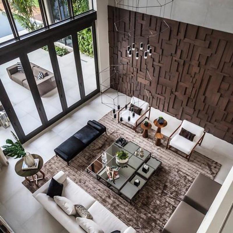 High view down into a living room with a Clérachic wireframe pendant hanging over a dark textured wall.