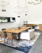 Cube-framed pendants hang above a wooden dining table with tan chairs and a patterned rug, from Clérachic.