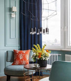 Clérachic wireframe pendant partly in view by a navy curtain and a green armchair, with a bunch of yellow flowers on the table below.