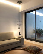 Small wireframe pendant in a living room with a sofa and a glass sliding door, with a cushion on the floor, from Clérachic.