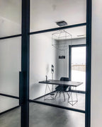 Wireframe pendant in a small office behind a black-framed glass door, with a desk and a chair, from Clérachic.