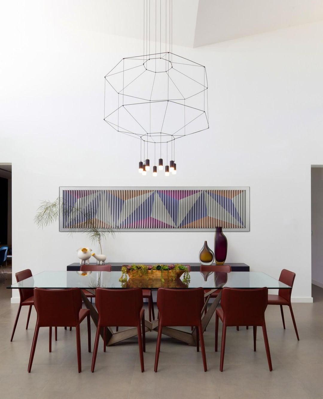 Clérachic wireframe pendant with a small cluster of lights over a glass dining table and red leather chairs.