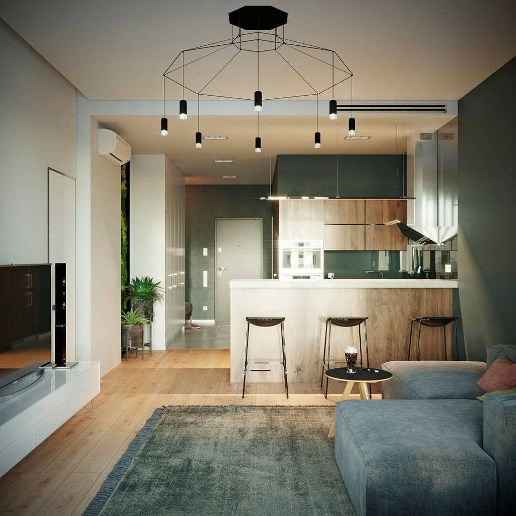 Wide black wireframe pendant with a canopy, lit over an open-plan kitchen and living room with a grey sofa, from Clérachic.