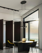 Octagonal wireframe pendant over a round black table with yellow and black chairs and a glass wall, from Clérachic.